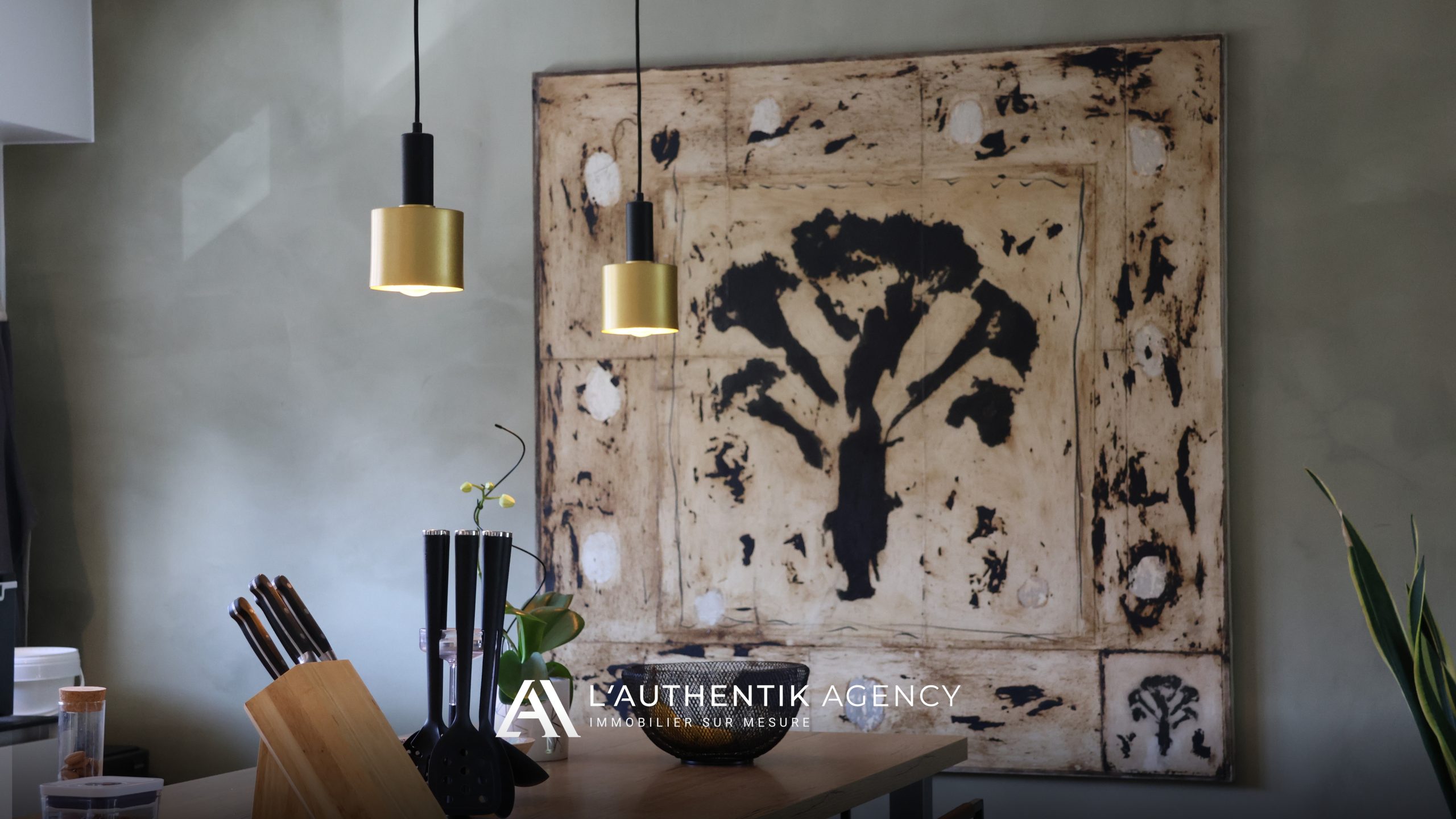 Focus sur le plan de travail de la cuisine, orné d'ustensiles, avec une œuvre d'art sur toile en arrière-plan ajoutant une touche artistique décorative sophistiquée.