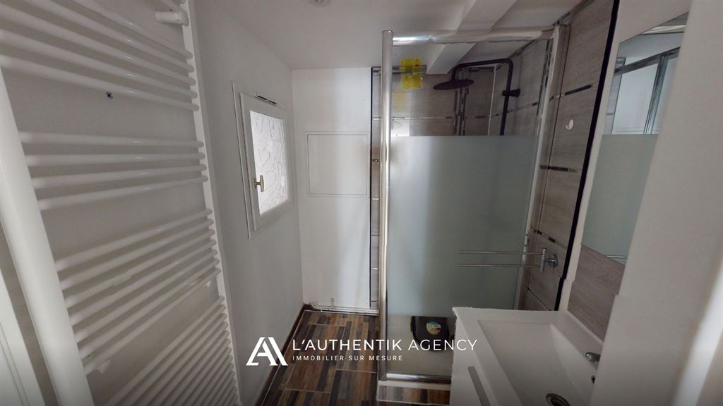 photographie de la salle d'eau avec douche à l'italienne, meuble vasque et sèche serviette.