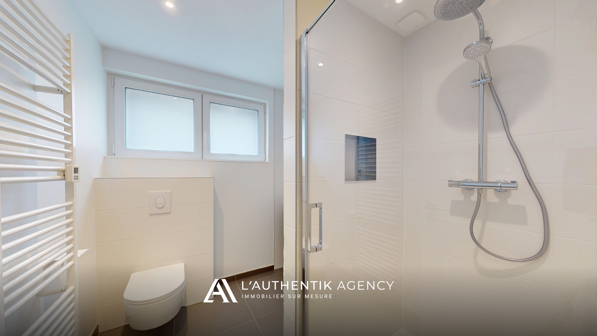 Salle d'eau avec sa douche à l'italienne, sèche serviette, wc suspendu et son meuble vasque