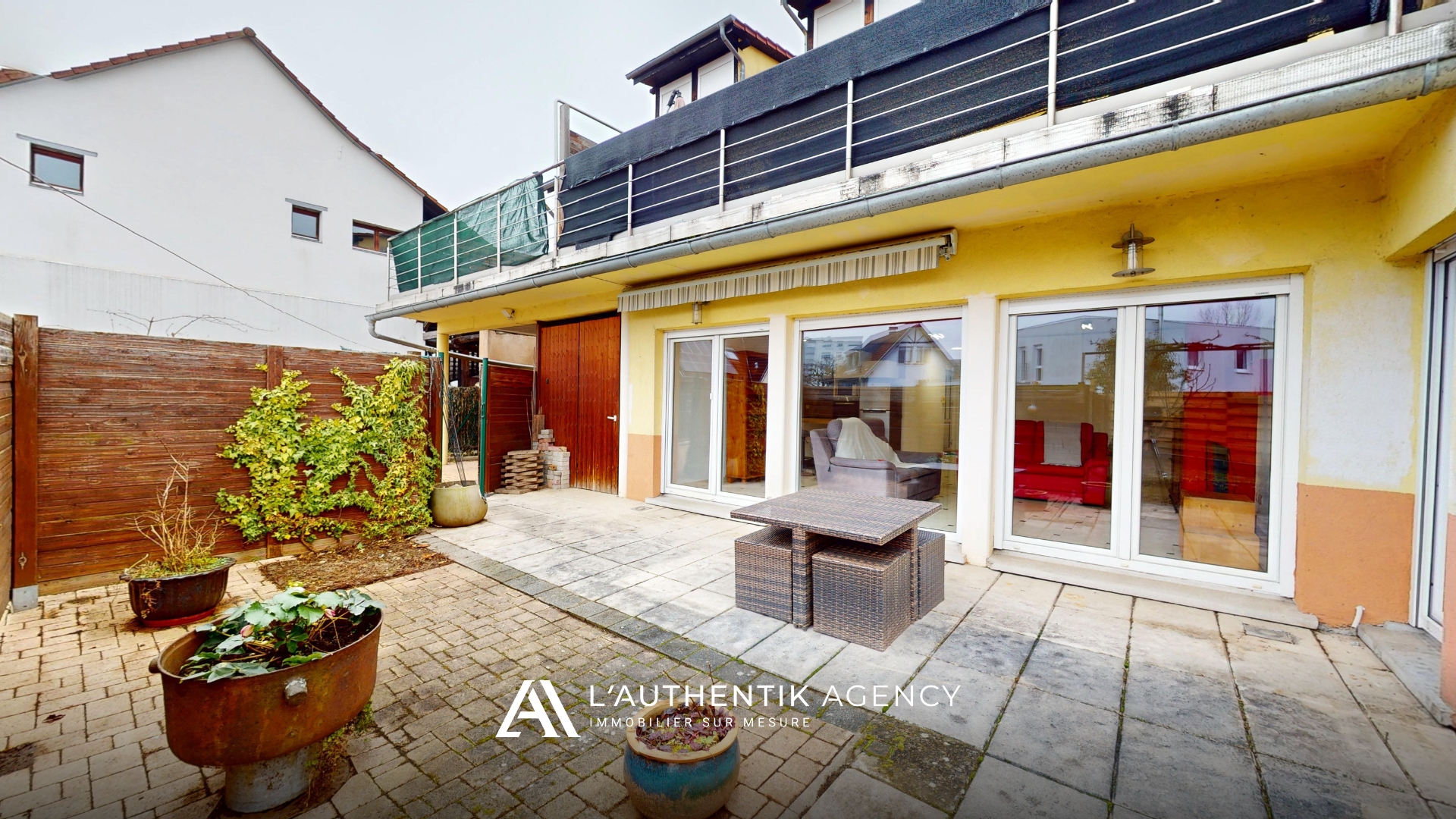 Vue de la façade depuis la terrasse et le jardin de l'appartement