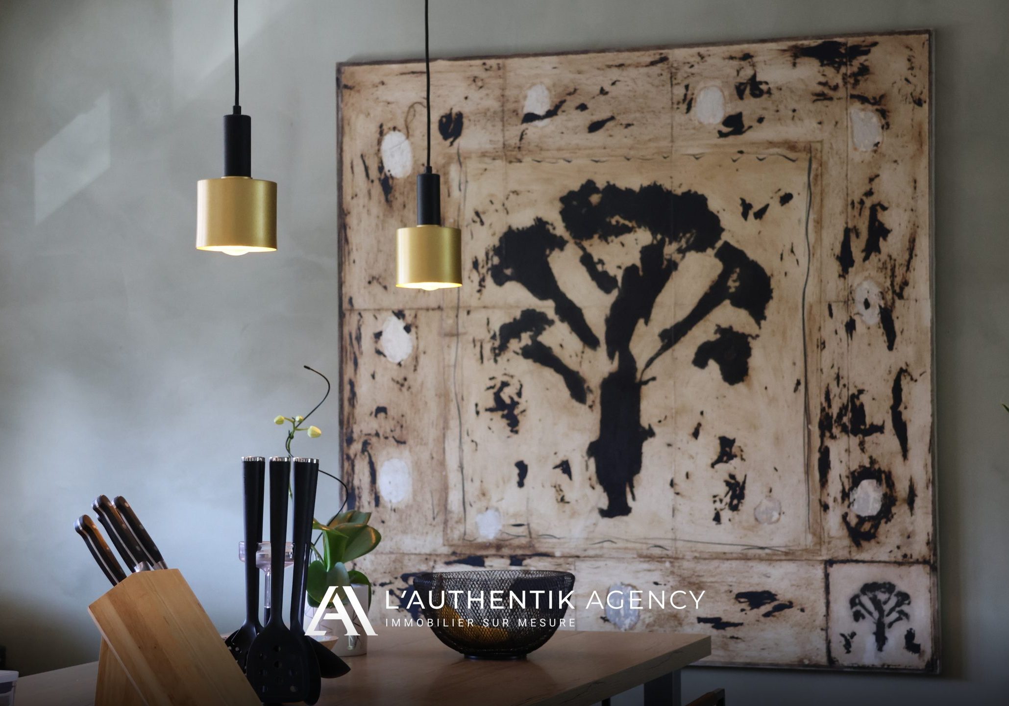 Focus sur le plan de travail de la cuisine, orné d'ustensiles, avec une œuvre d'art sur toile en arrière-plan ajoutant une touche artistique décorative sophistiquée.